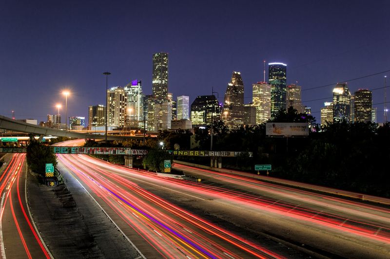 Downtown Houston skyline at night above freeway light trails