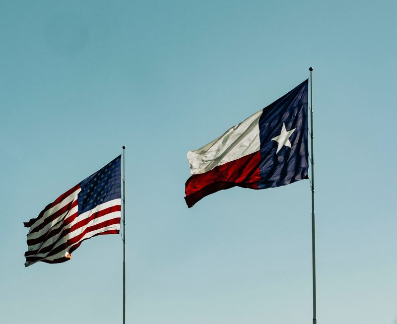 Texas and U.S. flags flying against a blue sky
